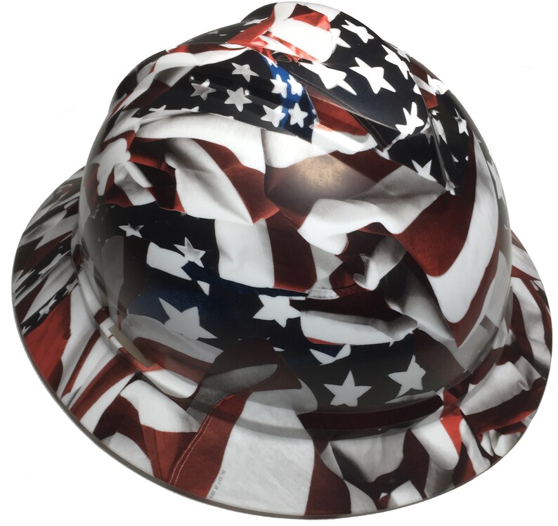 Puede incluir: Un casco blanco con un dise&ntilde;o de bandera americana roja, blanca y azul. La bandera est&aacute; impresa en toda la superficie del casco.