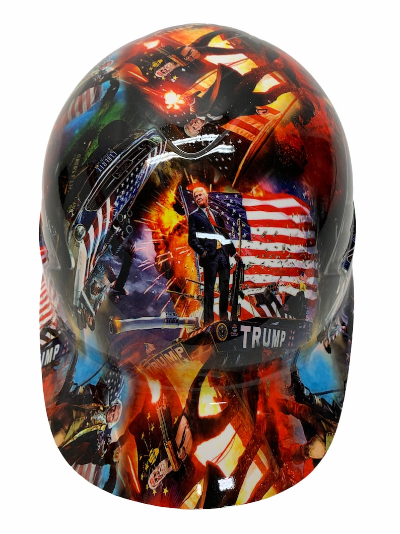 May include: A hard hat with a colorful design featuring images of Donald Trump, American flags, and patriotic imagery. The text "TRUMP" is visible on the hat.