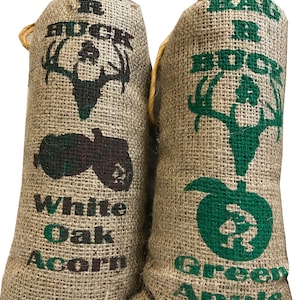 May include: Two burlap bags with a deer silhouette and text. The bag on the left says "Big Buck White Oak Acorn" and the bag on the right says "Big Buck Green Apple".
