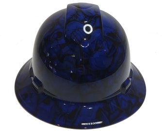 Pode incluir: Capacete de segurança azul com um design de caveira e ossos cruzados. O capacete tem um círculo branco na parte superior.