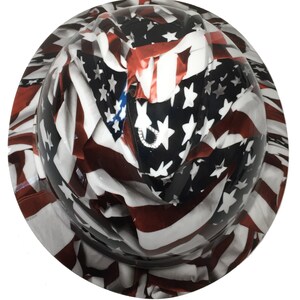 Puede incluir: Un casco de seguridad con un dise&ntilde;o de bandera estadounidense blanca, roja y azul. La bandera est&aacute; drapeada sobre el casco y parece ondear al viento.