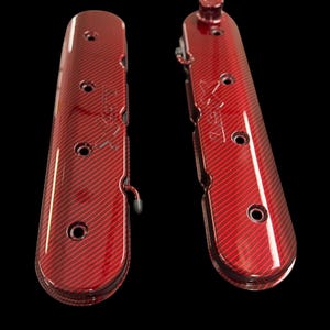May include: Two red carbon fiber engine valve covers with a glossy finish. Each cover has multiple holes and a textured pattern. The covers are designed for automotive use and are set against a black background.