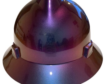 May include: A hard hat with a purple to blue iridescent finish. The hard hat has a wide brim and a smooth, glossy surface.