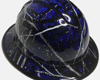 Pode incluir: Capacete de segurança camuflado azul e preto com aba larga. O capacete apresenta um acabamento brilhante e um padrão de folhas brancas e prateadas. O texto "Muddy Girl Camouflage" é visível na frente.