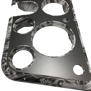 May include: A black and white patterned metal gauge panel with seven circular cutouts for gauges. The panel has a textured surface and a beveled edge.