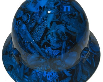 Pode incluir: Capacete de segurança azul com um design gráfico que apresenta uma variedade de imagens, incluindo pin-up girls, caveiras e águias. O texto "Gasoline 11" é visível no capacete.