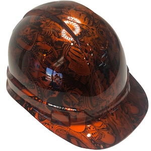 Könnte beinhalten: Ein Helm mit einem schwarzen und orangefarbenen Totenkopf- und Würfelmuster. Der Helm hat einen Schirm und einen Riemen.