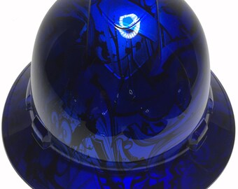 Pode incluir: Um capacete azul com um design abstrato preto e branco. O capacete tem uma faixa reflexiva ao redor da parte superior.