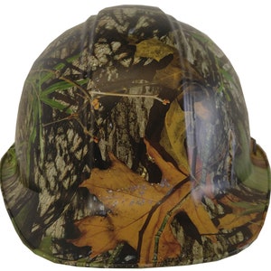 May include: A hard hat with a camouflage pattern featuring brown, green, and tan leaves and branches.