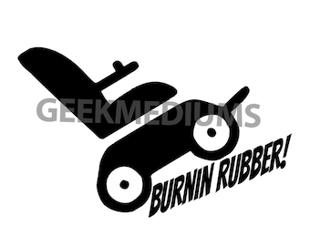 May include: A black graphic decal featuring a stylized illustration of a wheelchair with large wheels, positioned at an angle. The text GEEKMEDIUMS is visible in the center, and the phrase BURNIN RUBBER! is printed in bold, slanted letters below.