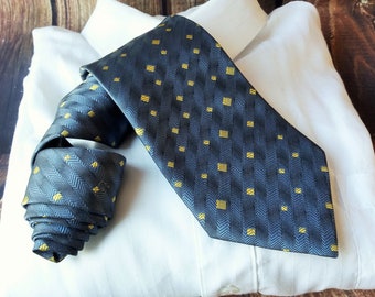 May include: A dark blue tie with a yellow geometric pattern on a white dress shirt.