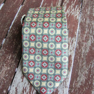 May include: A green and yellow patterned tie with red accents. The tie has a repeating pattern of circles and flowers.