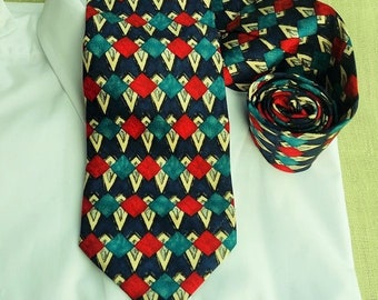 May include: A patterned tie with a geometric design in shades of red, blue, green, and yellow. The tie is made of silk and has a pointed tip.