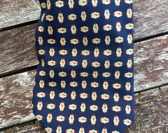 May include: A dark blue silk tie with a repeating pattern of small, light brown and red ovals.