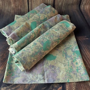 May include: Set of five fabric napkins in a green, brown, and purple camouflage pattern.