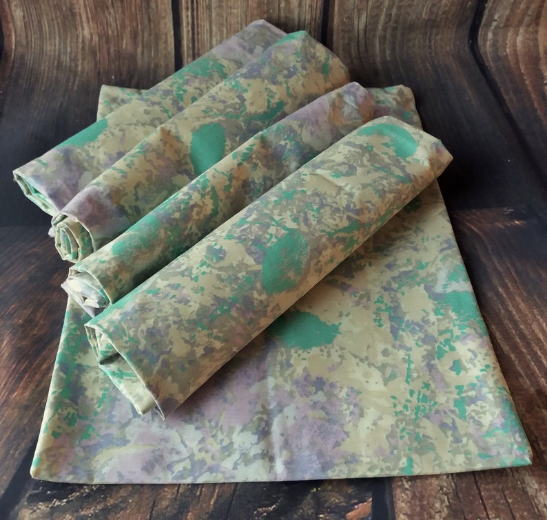 May include: Set of five fabric napkins in a green, brown, and purple camouflage pattern.
