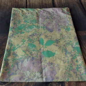 May include: A pillowcase with a floral pattern in shades of green, beige, and purple. The pattern features abstract flowers and leaves.