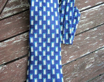 May include: A blue silk tie with a white geometric pattern. The tie has a narrow width and a pointed tip.