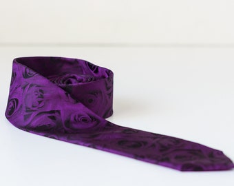 Puede incluir: Una corbata de seda morada con un patrón de rosas negras.