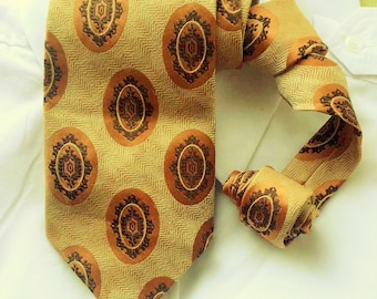 May include: A gold tie with a brown patterned design. The tie has a herringbone weave and features a repeating pattern of stylized circles.