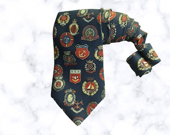 May include: A navy blue silk tie with a repeating pattern of gold and red nautical crests and emblems.