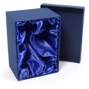 May include: A blue gift box with a satin lining. The box is open and the satin lining is visible. The box is made of cardboard and has a smooth finish.