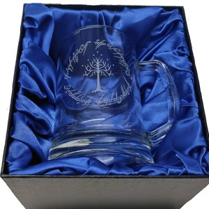 May include: A clear glass mug with a handle, featuring an etched design of the White Tree of Gondor and the inscription "One Ring to rule them all, One Ring to find them, One Ring to bring them all and in the darkness bind them" in Elvish script.