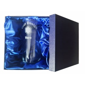 May include: A clear glass with an etched design that says "Your Design Here" inside a blue satin-lined box.