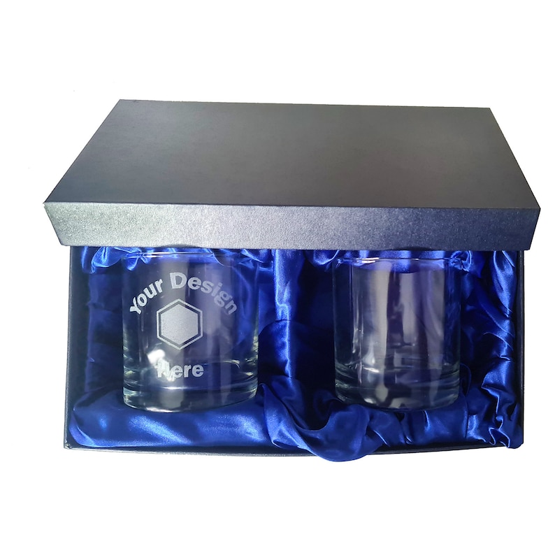 May include: Two clear glass tumblers with a blue satin lining inside a black gift box. One tumbler has the text "Your Design Here" etched on the side.