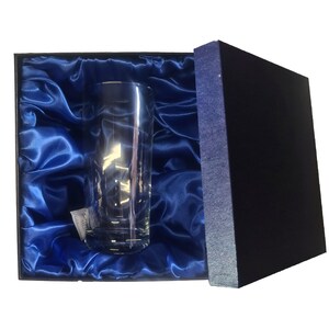 May include: A clear glass tumbler in a blue satin-lined box. The box is open and the glass is visible.