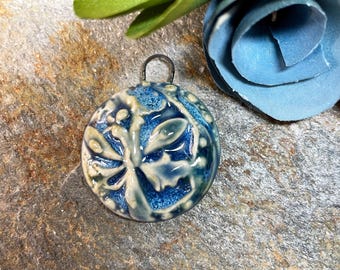 May include: A blue and white ceramic pendant with a dragonfly design. The pendant has a silver loop for hanging.