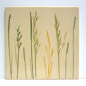 May include: A beige tile with a pressed floral design featuring green and yellow grasses.