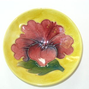 May include: A yellow ceramic plate with a raised, three-dimensional red hibiscus flower design.