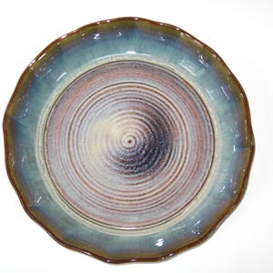 May include: A blue and brown ceramic plate with a scalloped edge and a swirling pattern in the center.