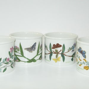 May include: Set of four white ceramic mugs with butterfly and floral designs. Each mug features a different butterfly species and floral arrangement.