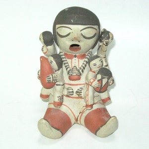 May include: Hand-painted ceramic figurine of a woman with four children, all with black hair and painted details. The woman is wearing a red and white striped dress and a necklace. The children are holding various objects, including a gourd and a doll.