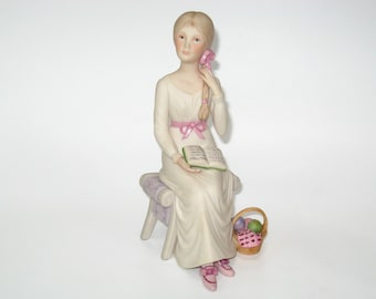 Figura de porcelana bizcochada Cybis ALICE de niña sentada con libro y cesta, 20 cm; estatuilla vintage firmada, en perfecto estado.