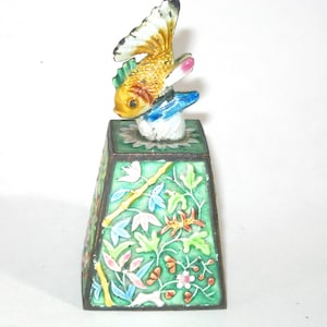 May include: A small, square, green and gold enameled box with a lid featuring a hand-painted, three-dimensional, yellow and blue fish.