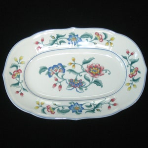 May include: White oval serving dish with a blue and green floral design. The flowers are pink, yellow, and blue.