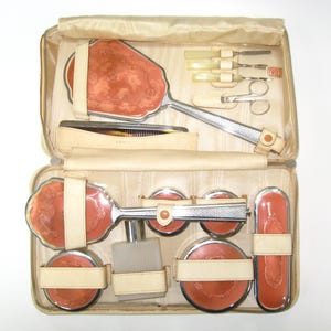 May include: A white ceramic mug with a black handle and the text "But First, Coffee" in a bold, black font. The mug is set against a blurred background, suggesting a cozy setting.