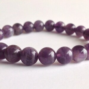 May include: A purple amethyst gemstone bracelet with round beads.