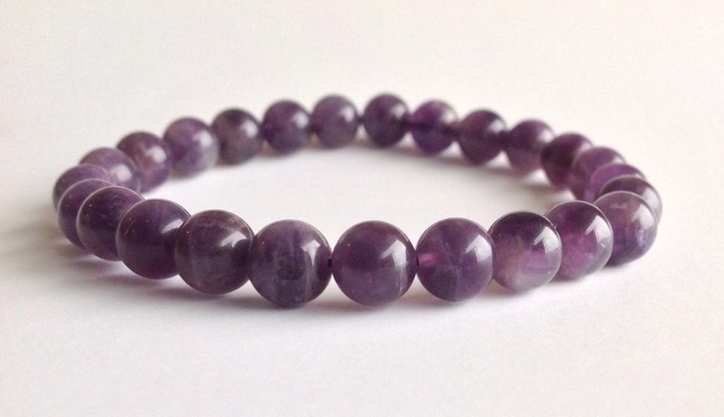 May include: A purple amethyst gemstone bracelet with round beads.