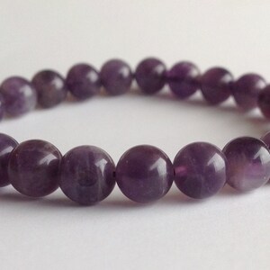 May include: A purple amethyst gemstone bracelet with round beads.