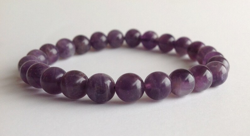 May include: A purple amethyst gemstone bracelet with round beads.