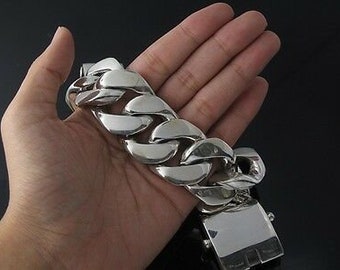 May include: A thick silver chain bracelet with a large, chunky link design. The bracelet is shown on a person's hand.