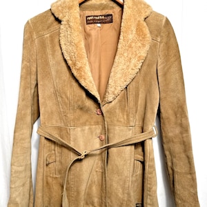 Puede incluir: Chaqueta de ante marrón claro con cuello de borrego y cinturón a juego. La chaqueta tiene cierre de botones y dos bolsillos delanteros. La etiqueta dice "Splend-id Ltd."