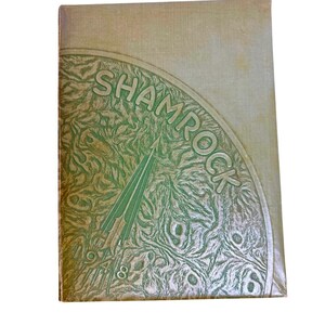 Puede incluir: Un anuario vintage con una cubierta verde. La cubierta presenta la palabra "SHAMROCK" en un diseño semicircular, con una flecha verde y el año "1948" debajo. La cubierta tiene un patrón texturizado.