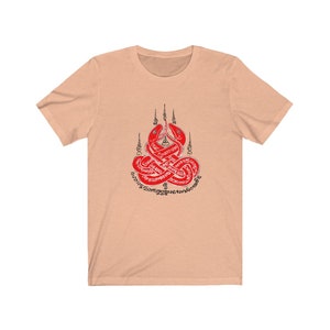 May include: A peach-colored t-shirt with a red and black design of two intertwined snakes with Thai script surrounding them.