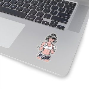 May include: A sticker featuring a stylized illustration of a female Muay Thai fighter. The fighter is depicted in a white sports bra, black and white shorts, and wrapped hands. The sticker is placed on a laptop.