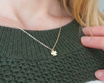 May include: A gold chain necklace with a small four-leaf clover pendant.